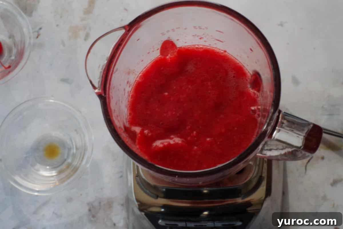 Frozen strawberries and Daiquiri mix blended together in bowl of a blender.