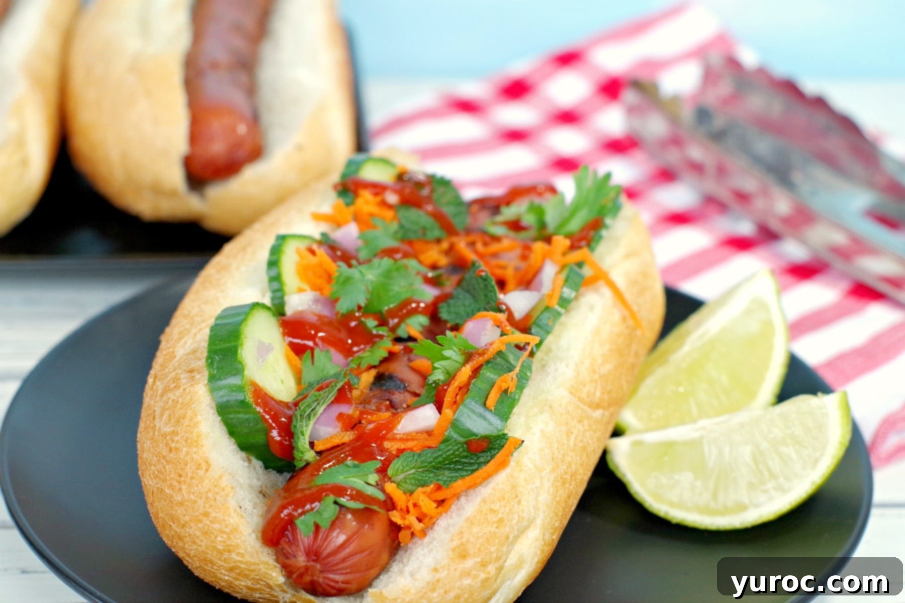 Banh Mi Turkey Hot Dog Twist 2 Banh Mi turkey hot dog on black plate with lime wedges, showcasing fresh ingredients and vibrant colors.
