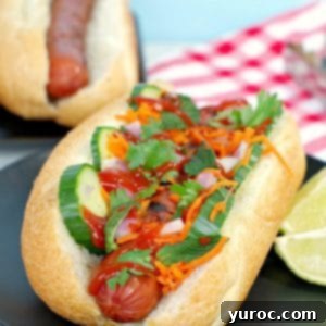 Banh Mi Turkey Hot Dog Twist 11 Banh Mi turkey hot dog on black plate with lime wedges, a delightful meal.