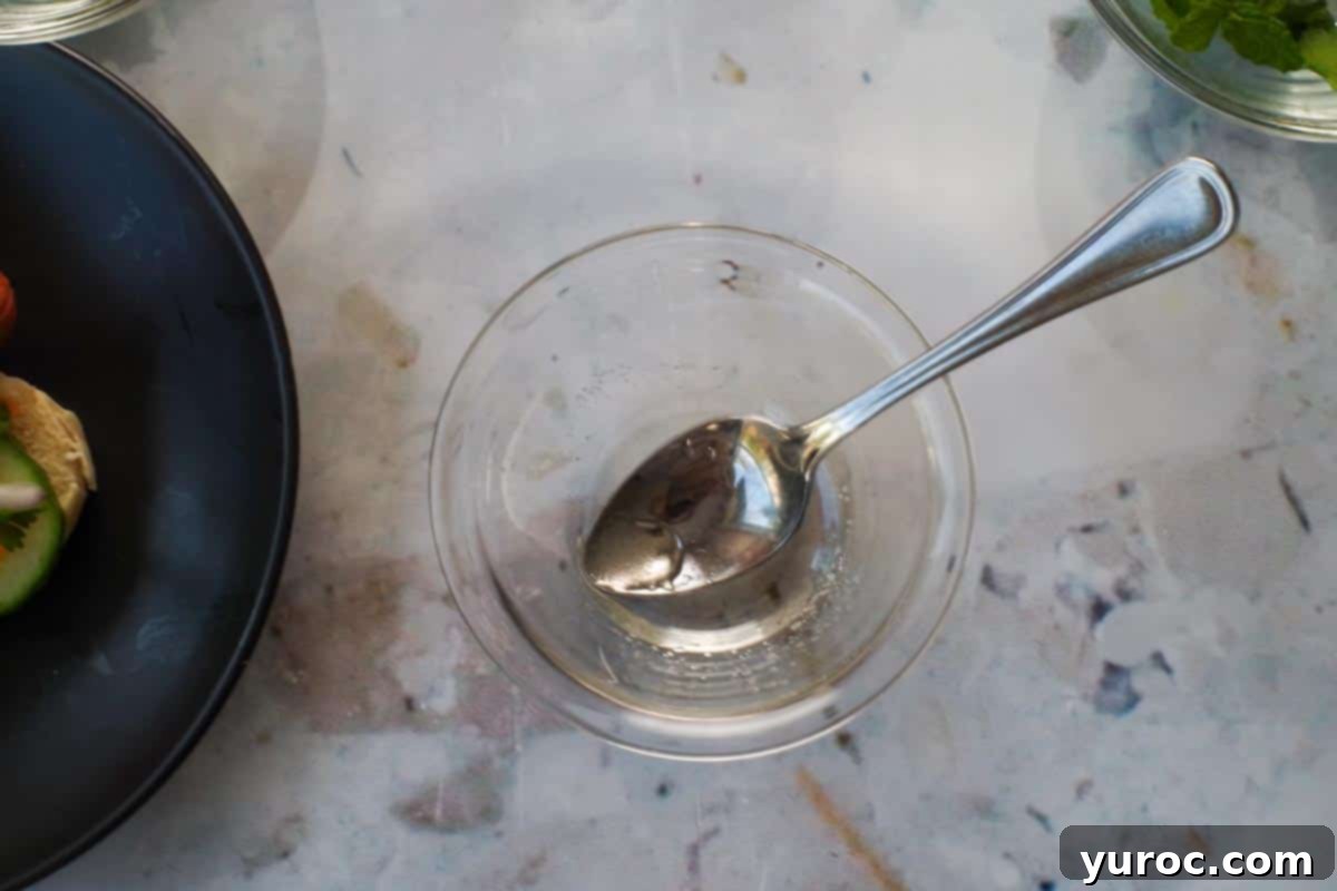 Banh Mi Turkey Hot Dog Twist 6 Sugar and rice vinegar mixed together in a small glass bowl with a spoon, forming the tangy dressing.