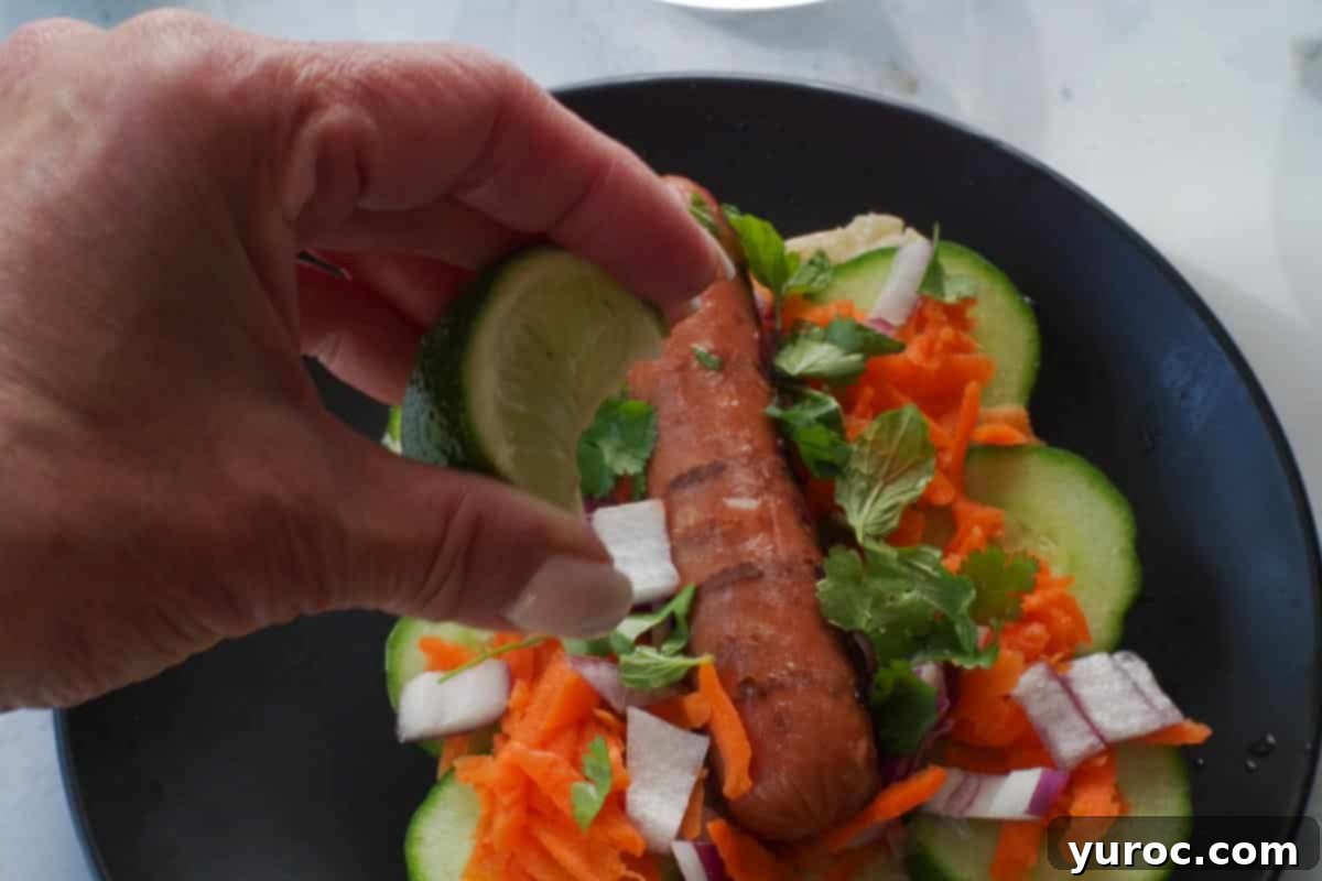 Banh Mi Turkey Hot Dog Twist 8 Lime wedge being squeezed over a Banh Mi Turkey Hot Dog, adding a final touch of brightness.