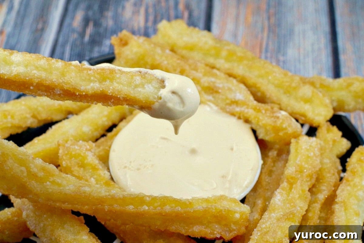 Churros being dipped in dulce de leche sauce