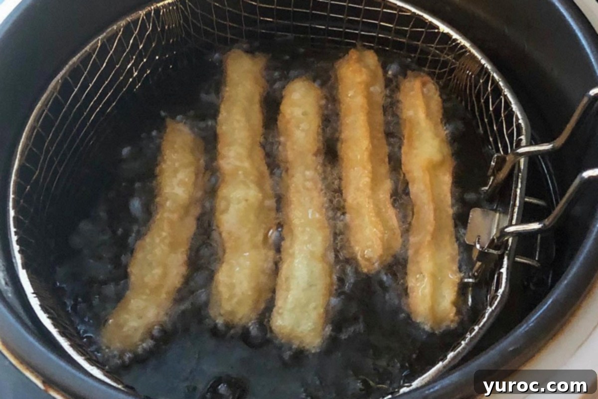 Churros being cooked in deep fryer.
