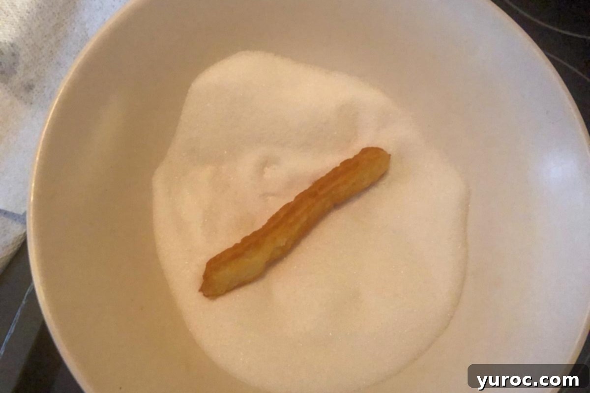 Churro being rolled in sugar.