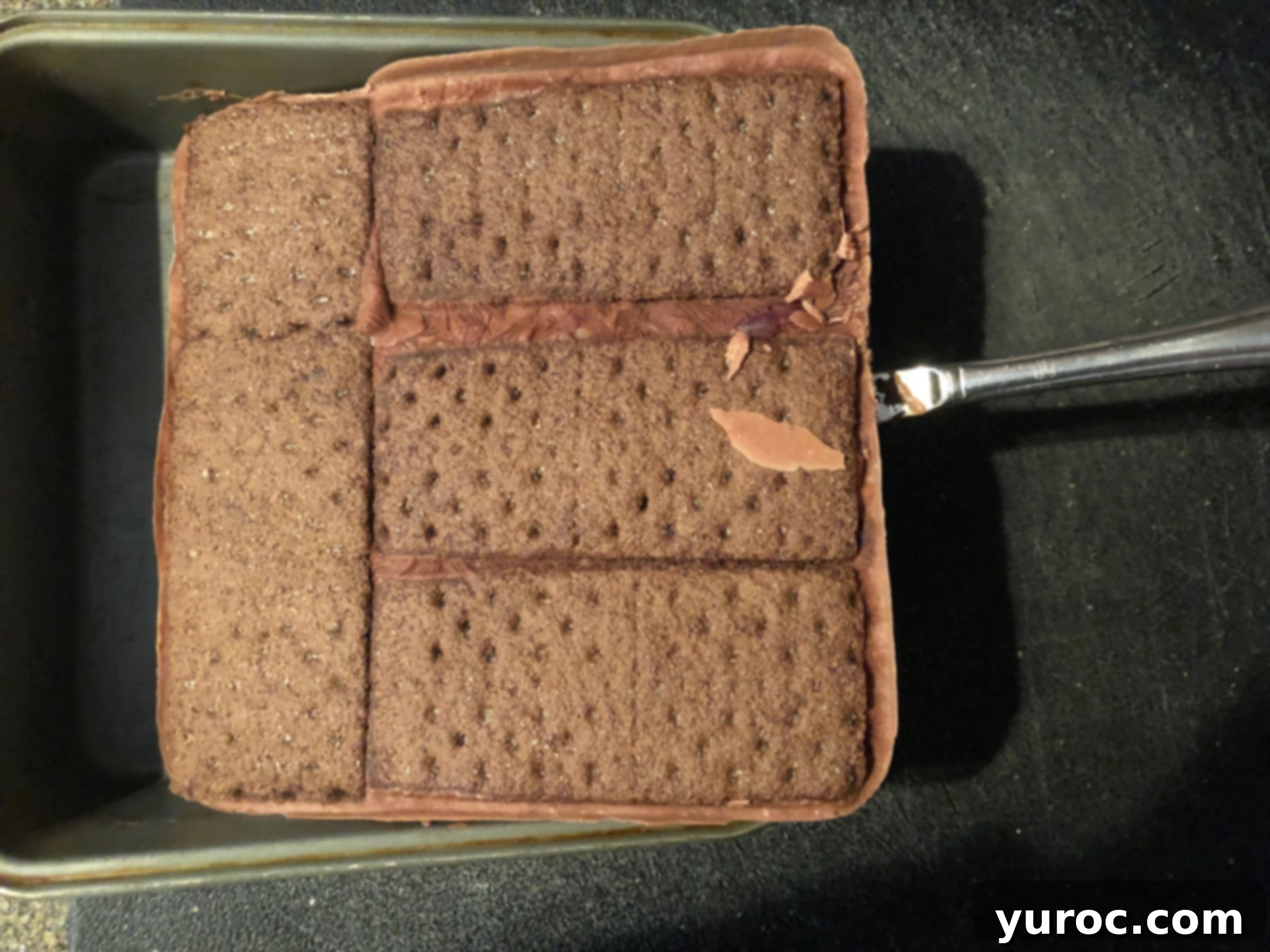 The solid block of ice cream sandwiches being lifted from the pan onto a cutting board.
