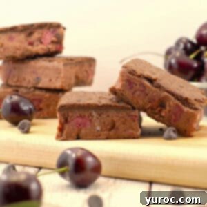 WW black forest ice cream sandwiches on cutting board with more stacked in back and bowl of cherries in background