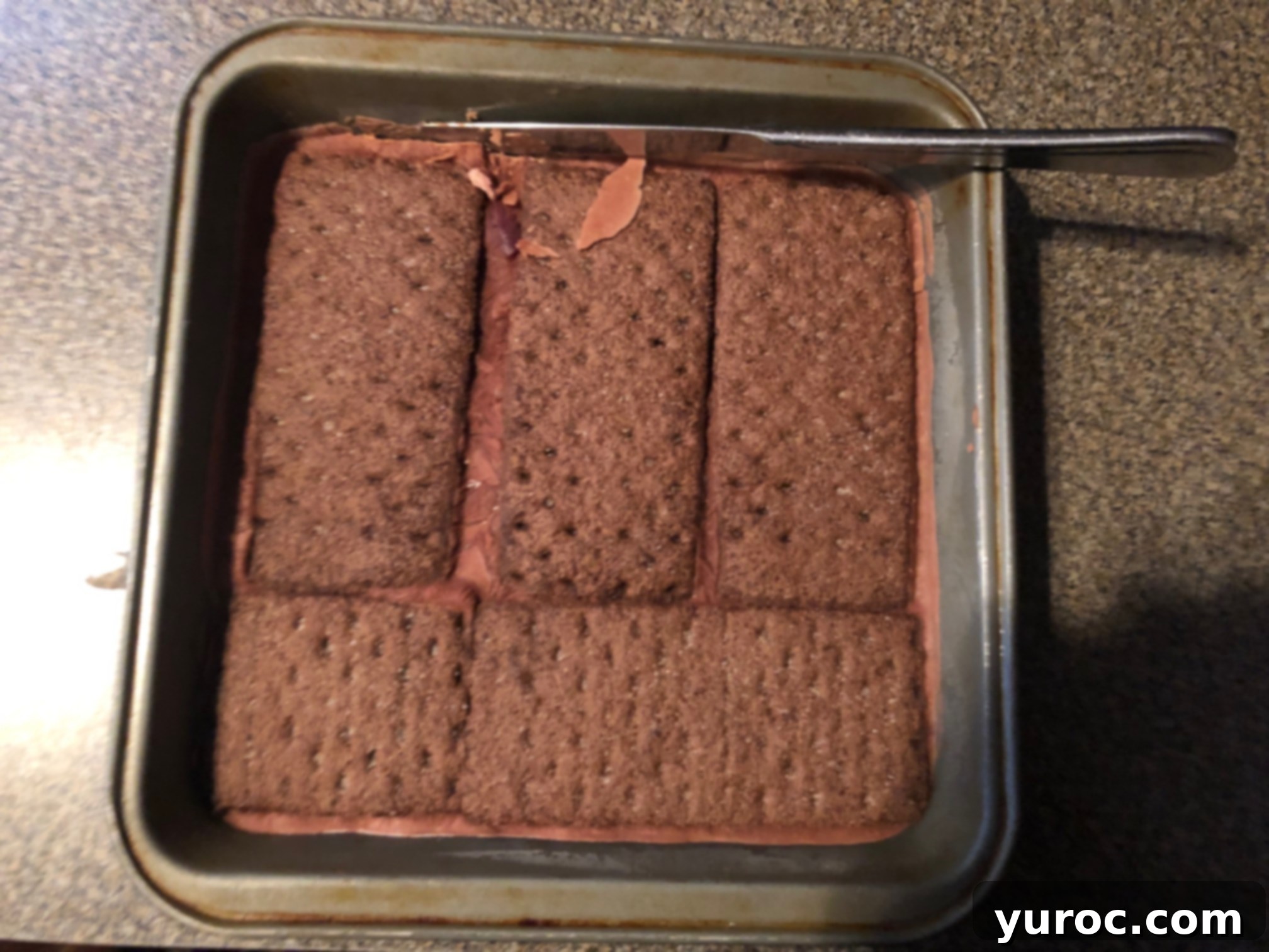 A knife being used to loosen the edges of the frozen ice cream sandwich slab from the baking pan.