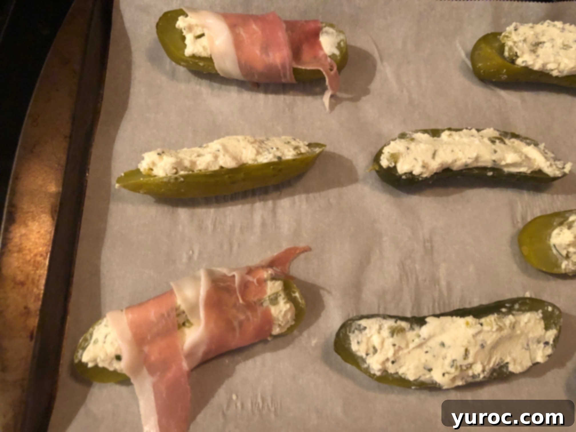 Creamy Boursin Pickle Bites 13 Multiple pickle halves securely wrapped in prosciutto, with the ends tucked underneath, arranged on a baking sheet