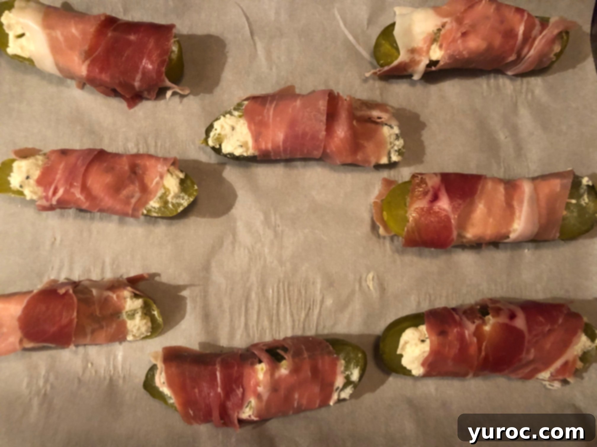 Creamy Boursin Pickle Bites 14 All prosciutto-wrapped Boursin stuffed pickles neatly arranged on a parchment-lined baking sheet, ready for the oven