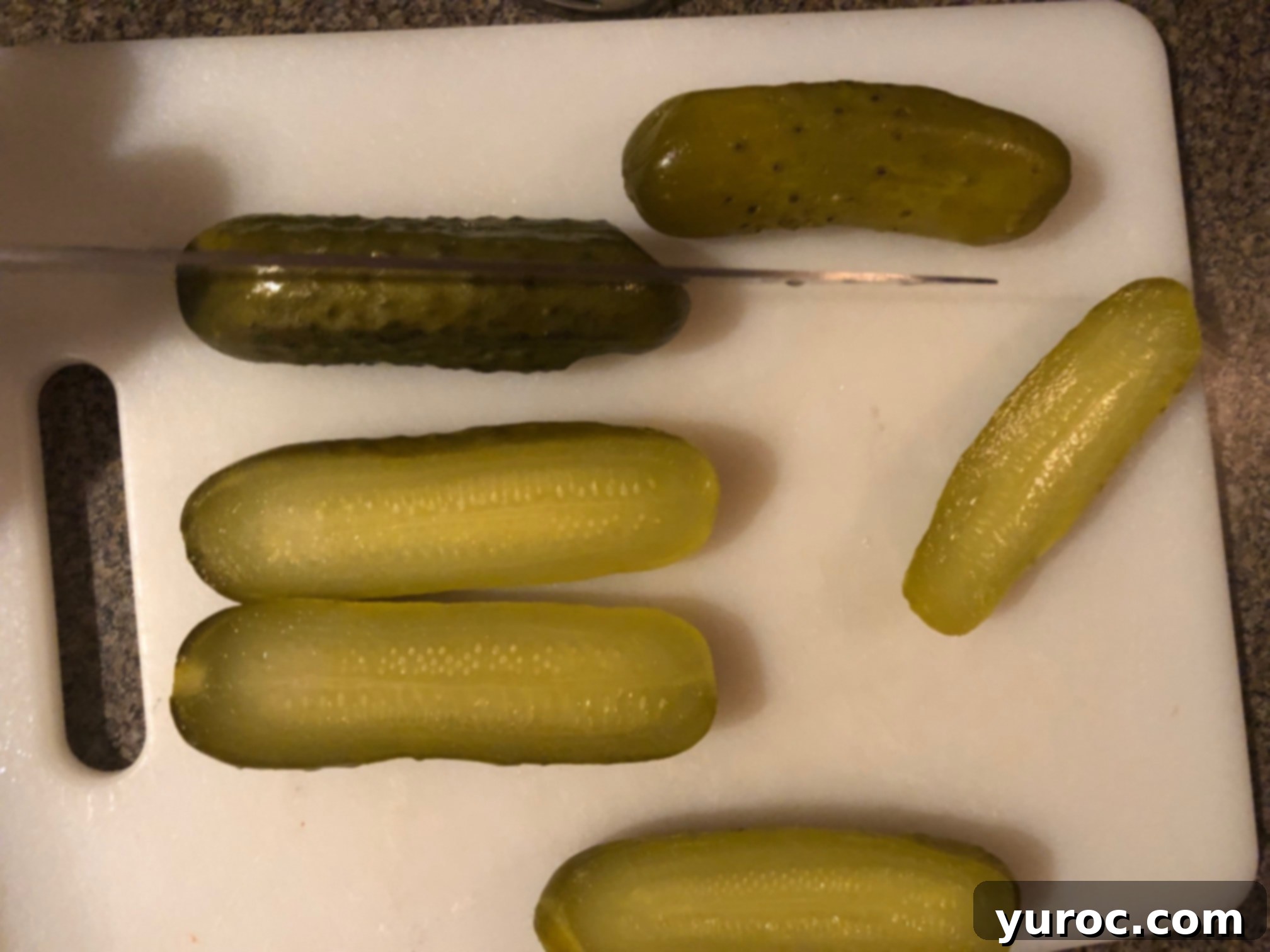 Creamy Boursin Pickle Bites 4 Whole dill pickles being carefully sliced lengthwise down the center on a cutting board, preparing them for stuffing