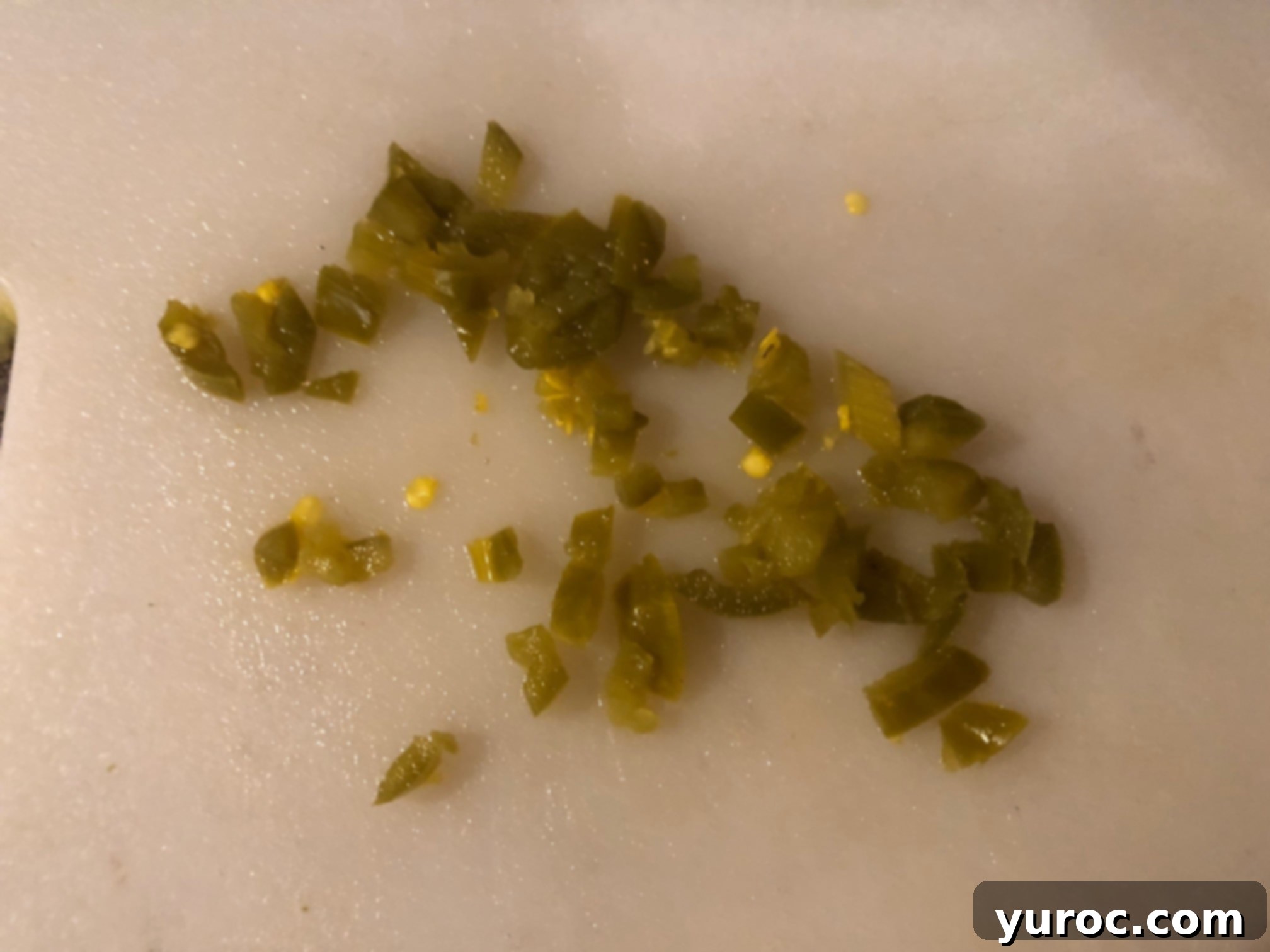 Creamy Boursin Pickle Bites 8 A small pile of finely chopped pickled jalapeños on a cutting board, ready to be mixed into the Boursin cheese