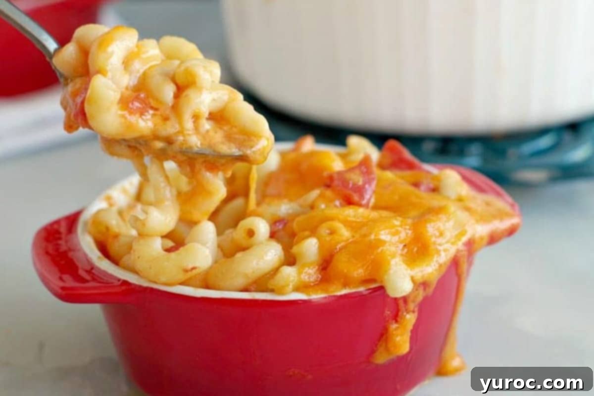 Mac and Cheese with tomatoes being lifted out of red bowl with spoon