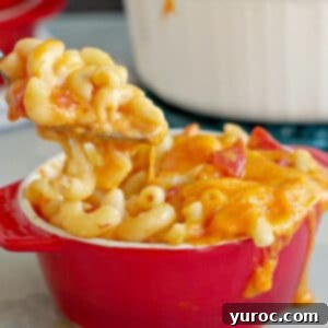 Mac and Cheese with tomatoes being lifted out of red bowl with spoon