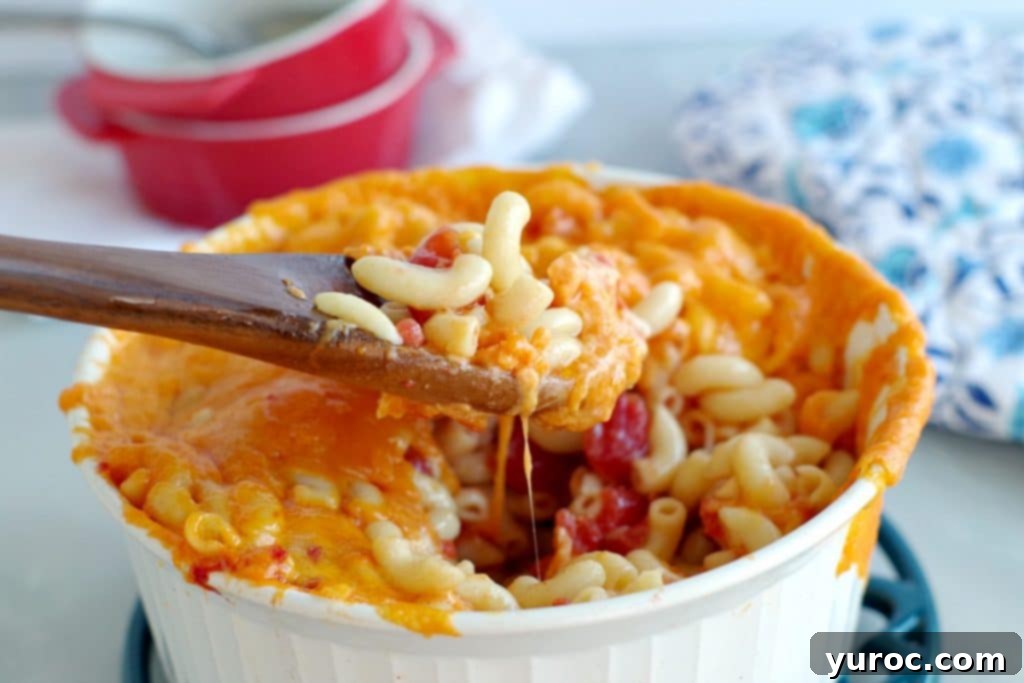 Mac and Cheese in a white casserole bowl with wooden spoon scooping it out