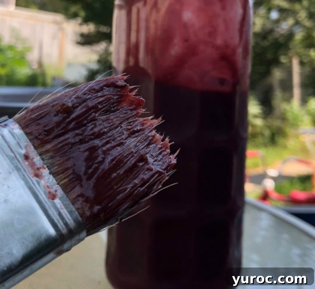 A bottle of delicious Saskatoon Berry BBQ sauce prominently displayed alongside a BBQ brush, ready for grilling.