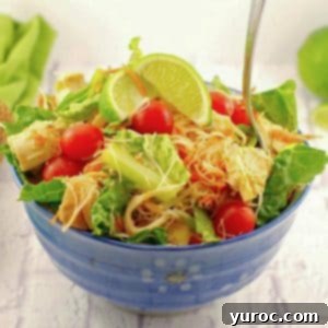 Thai Chicken Noodle Salad in a blue bowl on a white surface with a green napkin in the background, a perfectly plated dish.