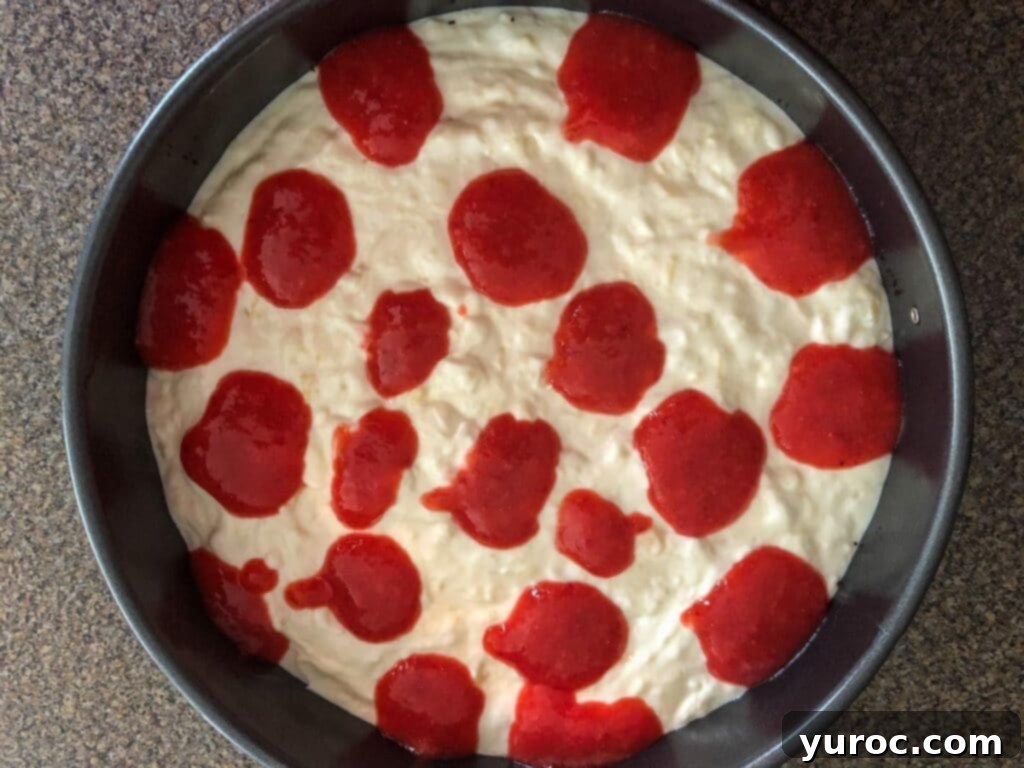Generous dollops of bright red strawberry mixture strategically placed on top of the white pina colada cheesecake layer.