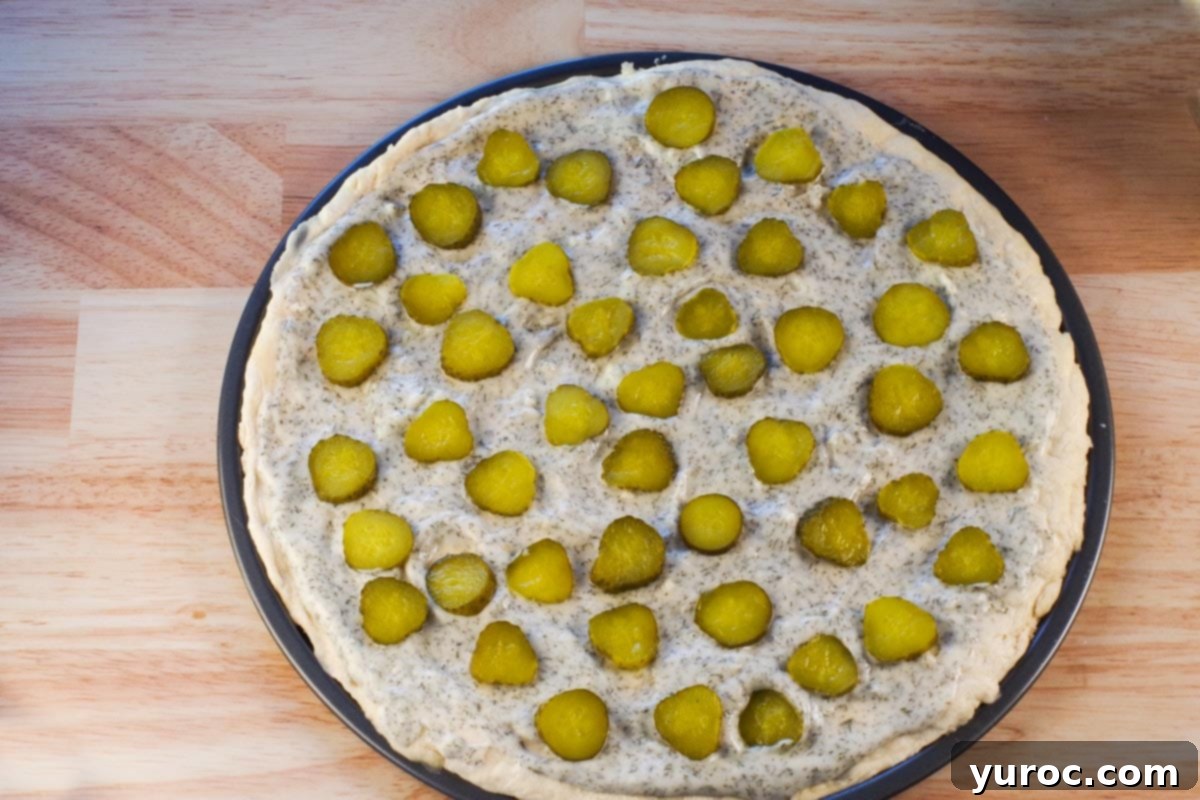 Pickle slices added to pizza.