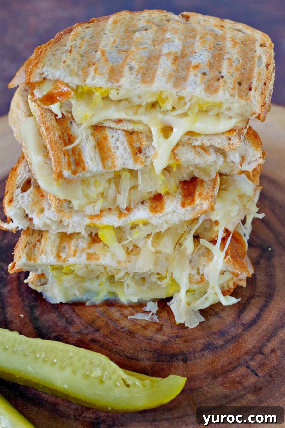A WW Turkey Reuben stacked on a wooden surface with a dill pickle.