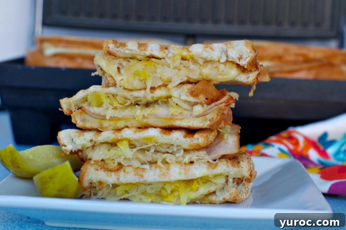 A Turkey Reuben Sandwich stacked on a white plate in front of a panini press.