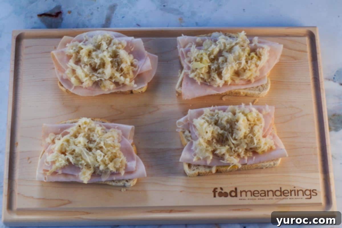 Sauerkraut on top of turkey covered bread slices on cutting board.