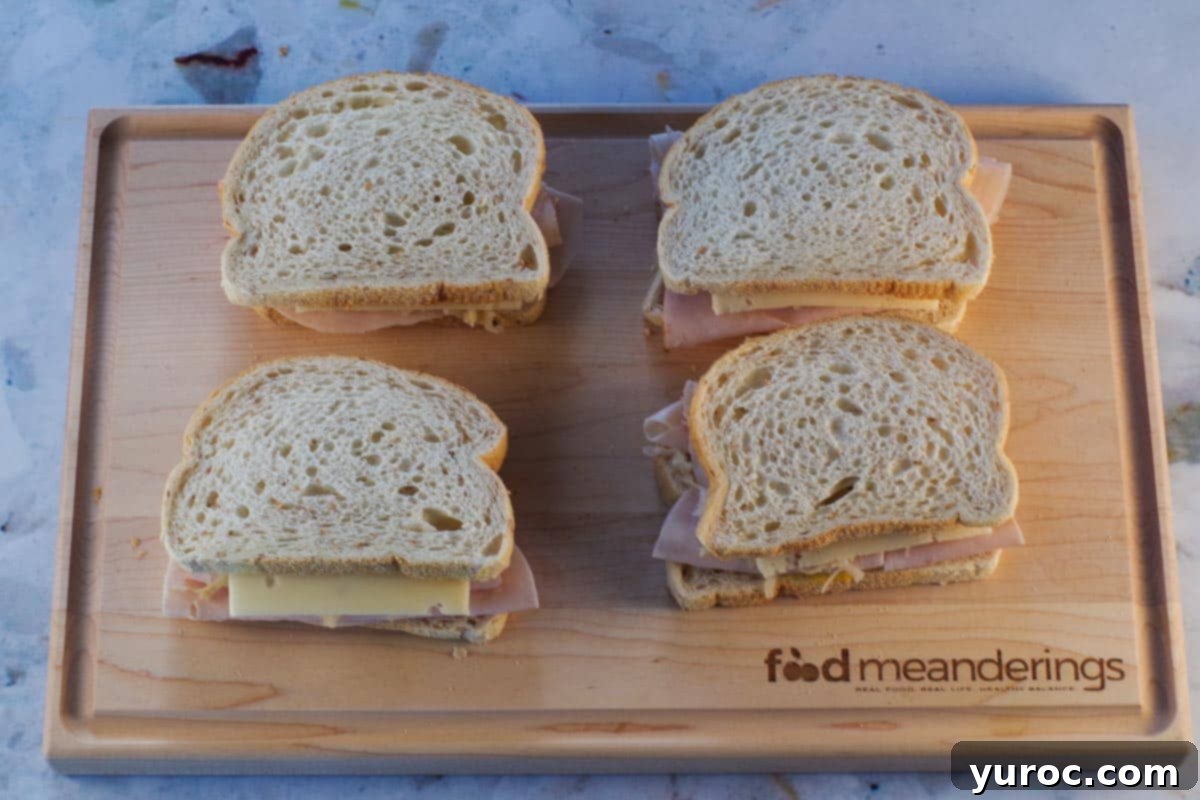 Slice of bread topping all 4 Turkey Reuben sandwiches on cutting board.