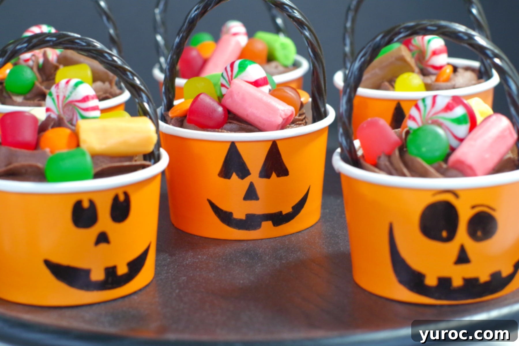 Halloween Jack o'latern cupcakes on a black platter, showcasing the candy-filled centers and festive decorations