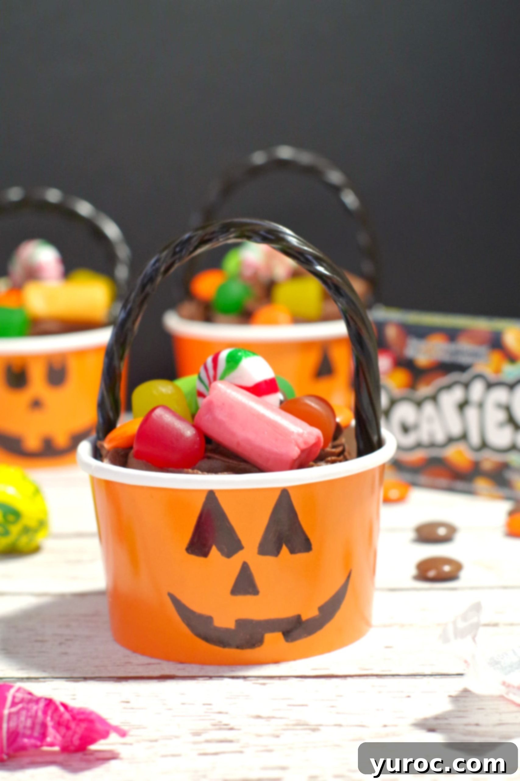 Halloween Jack o'latern bucket cupcake with candy strewn around, a perfect visual of a festive treat