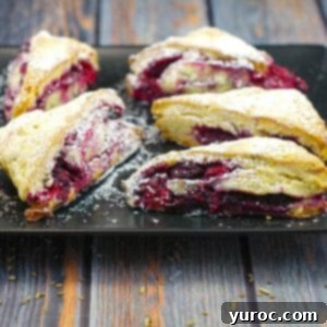 raspberry and lemon scones on a black platter on blueish faux wooden surface