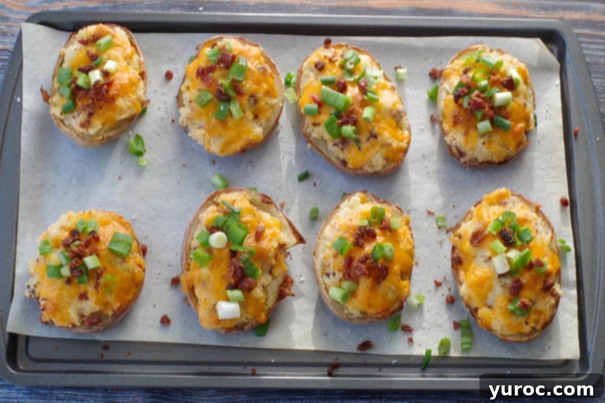 Freshly baked Caesar twice baked potatoes, hot and golden from the oven, displayed on a parchment-lined baking sheet, their cheesy tops perfectly melted and slightly browned.
