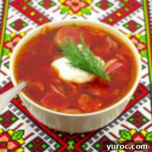Easy Beef Borscht with Canned Beets 10 borscht soup in a beige bowl on a Ukrainian patterned tablecloth