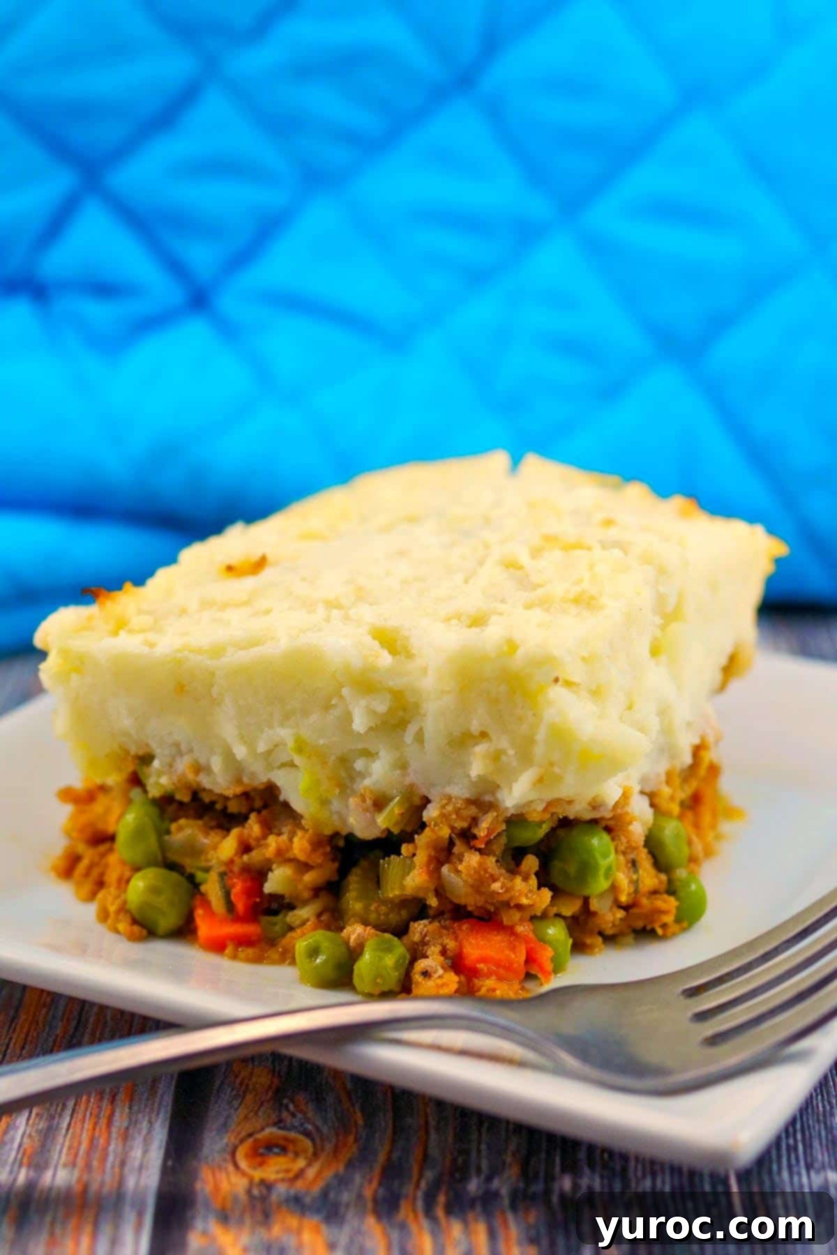 Smart Turkey Shepherd's Pie 12 Ground turkey shepherd's pie on a white plate with a fork and a full glass pan of the pie in the background, showcasing its delicious layers.