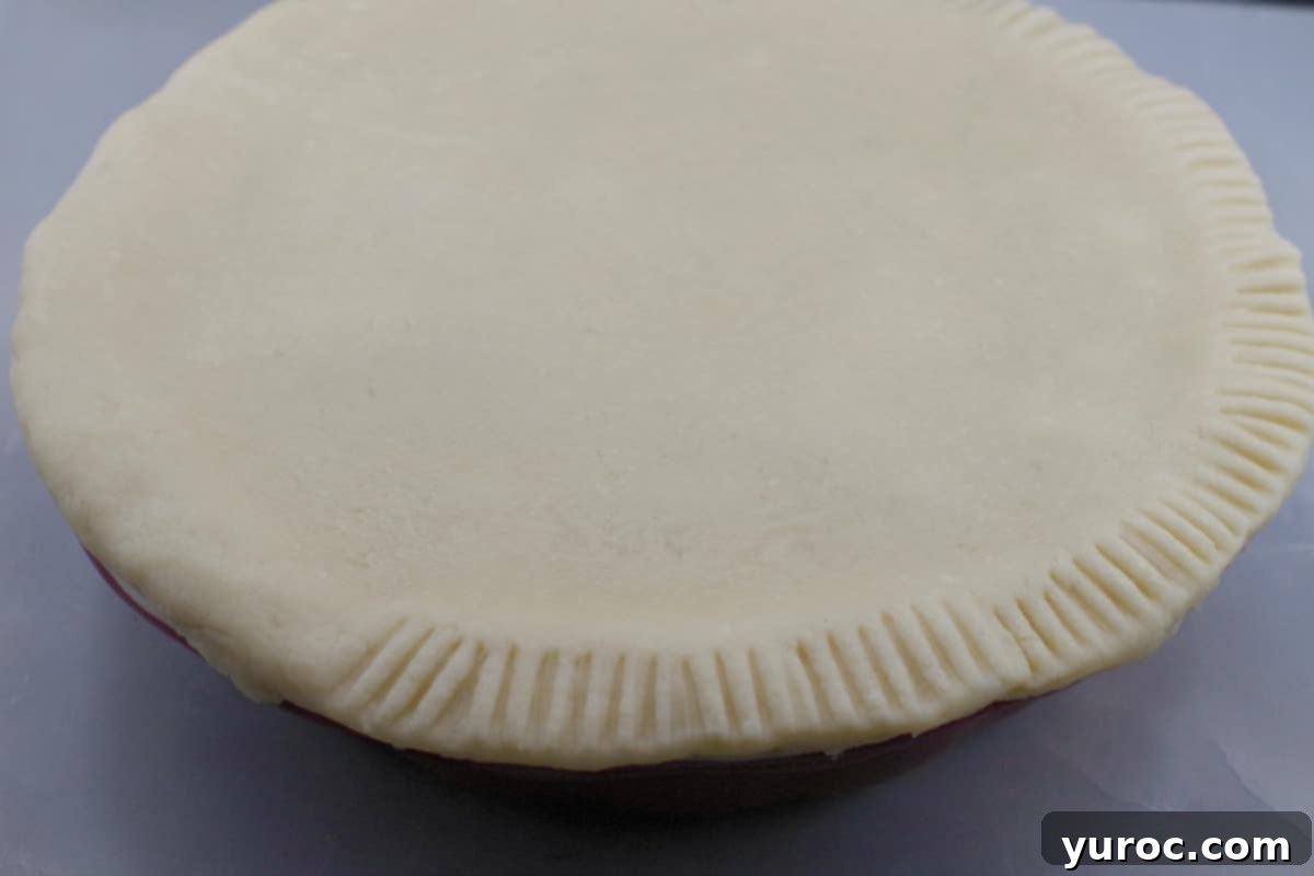 Saskatoon Berry Pie: Mastering the Filling and Sauce 11 pie crust edges being pleated with a fork
