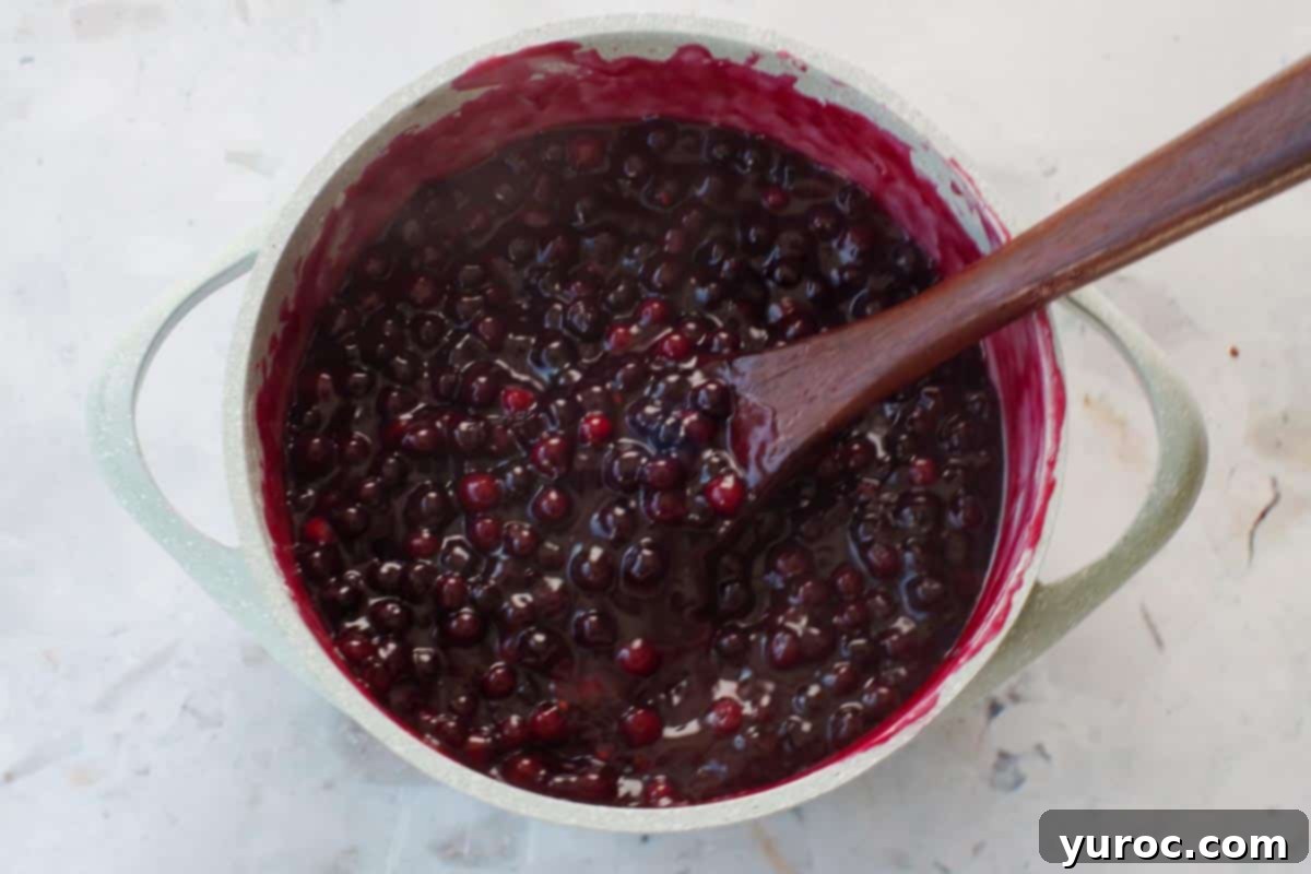Saskatoon Berry Pie: Mastering the Filling and Sauce 7 Saskatoon berry sauce mixture thickened in blue pot with wooden spoon.
