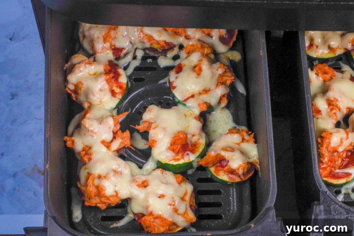 Fully cooked and melted Buffalo Chicken Zucchini Pizza Bites in an air fryer basket, ready to be served.