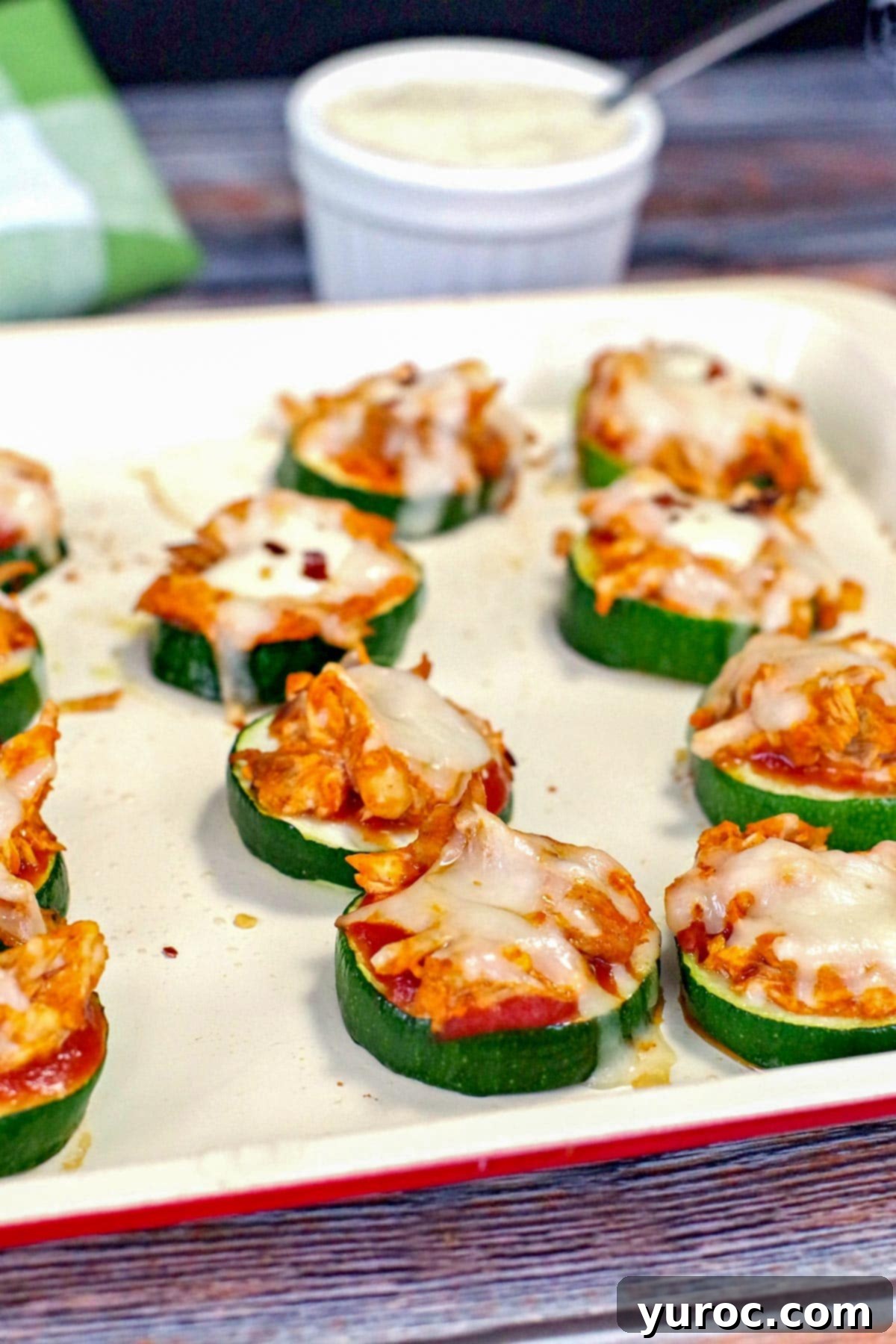 A baking tray filled with vibrant Buffalo Chicken Zucchini Pizza Bites, showcasing their appealing golden-brown cheese and toppings.
