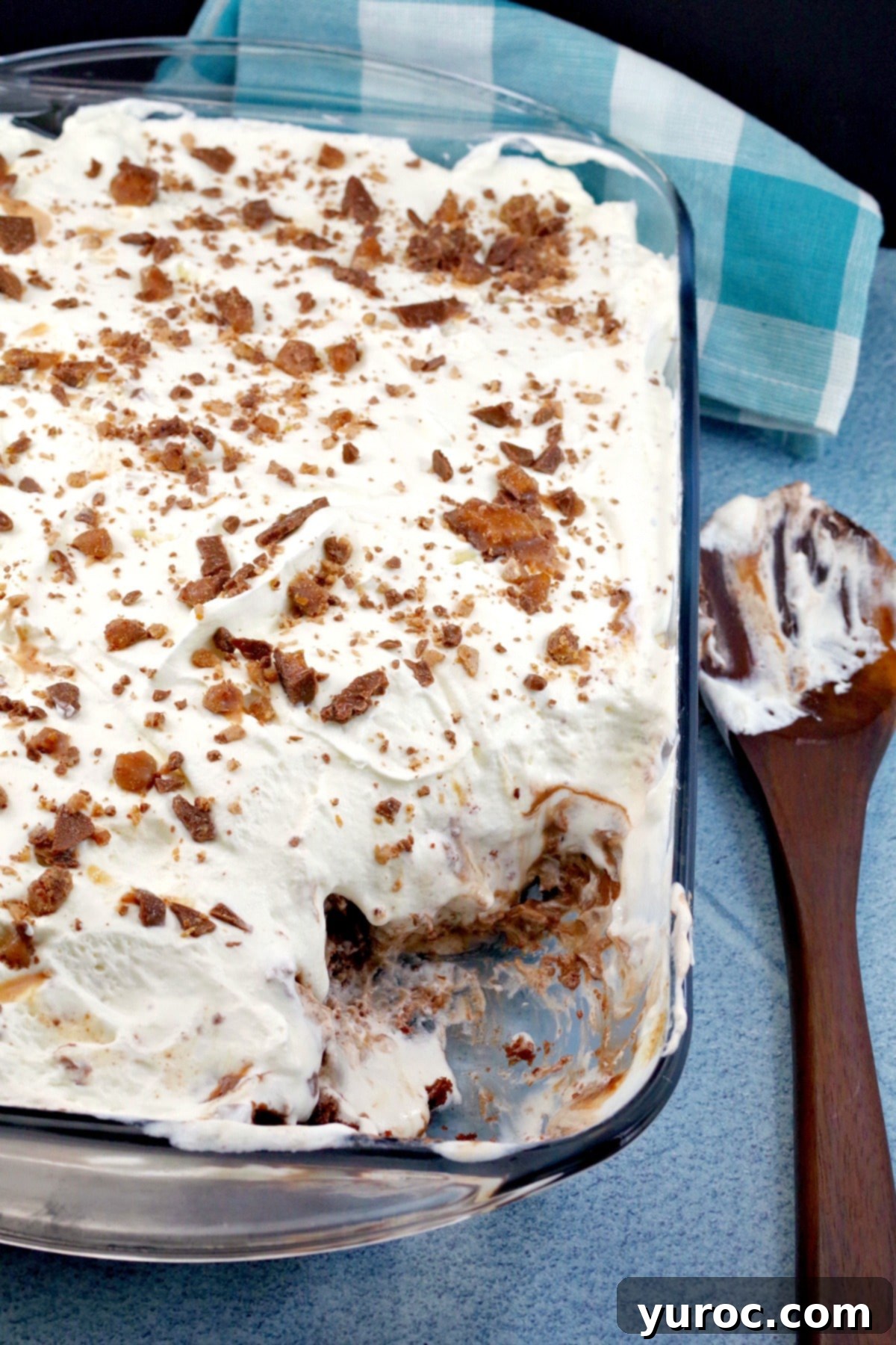 Skor Toffee Crunch Bars 3 Skor bar dessert recipe in 9X13 glass pan, with some removed and wooden spoon to the right side, showcasing its irresistible layers.