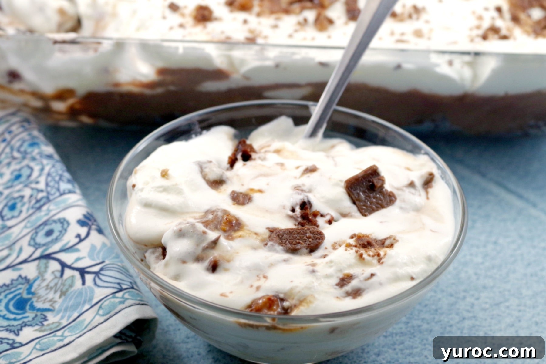Skor Toffee Crunch Bars 8 Bowl of Skor Bar Dessert in front and pan of Skor Bar dessert in background, emphasizing its creamy and crunchy appeal.