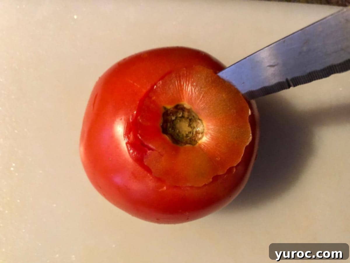 knife cutting off top of tomatoes with a cutting board