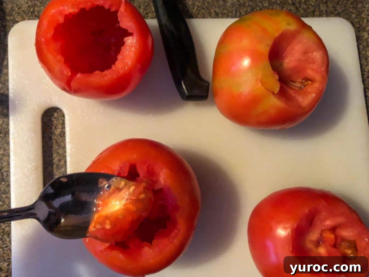 spoon scooping out inside of tomato