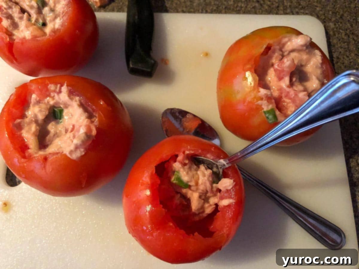 tuna mixture being stuffed back into tomatoes