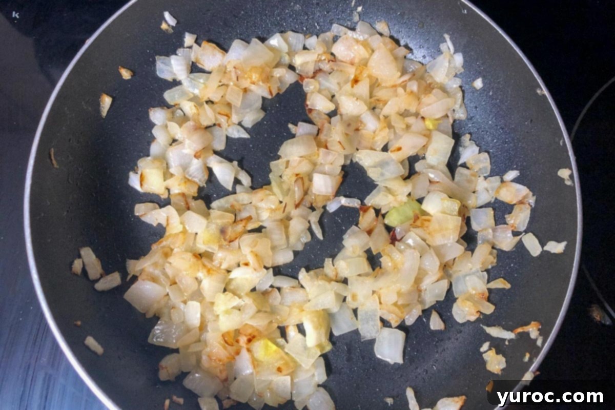 Chopped onions being fried in butter in a separate frying pan.