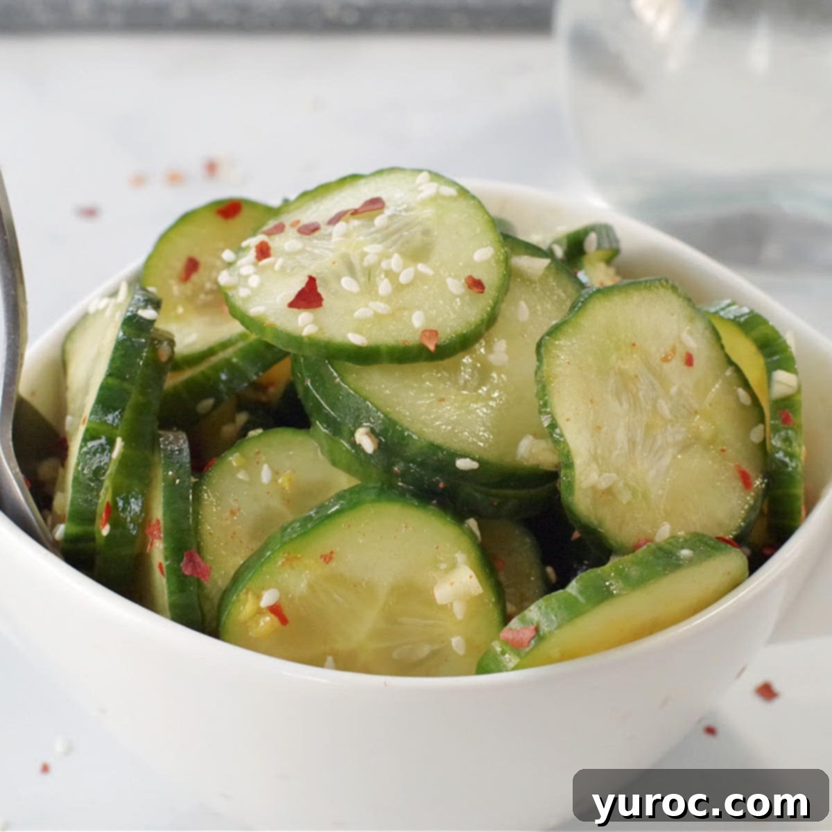 A bowl of Quick Cucumber Kimchi on a grey marble counter.