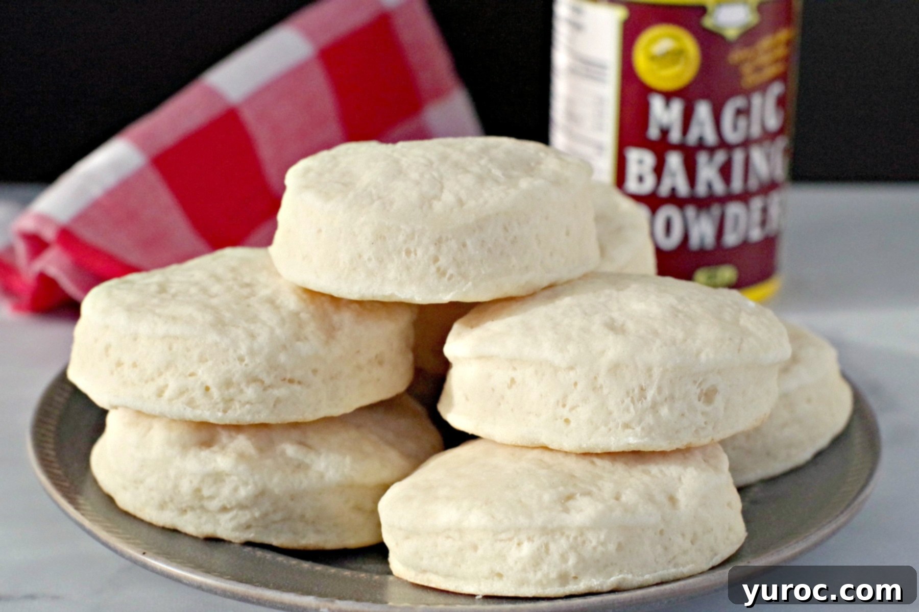 Super soft and fluffy old-fashioned baking powder biscuits piled on a plate, with a container of baking powder in the background. Perfect for breakfast or as a side dish.