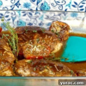 Balsamic chicken with tomatoes in a glass dish with aqua blue spatula