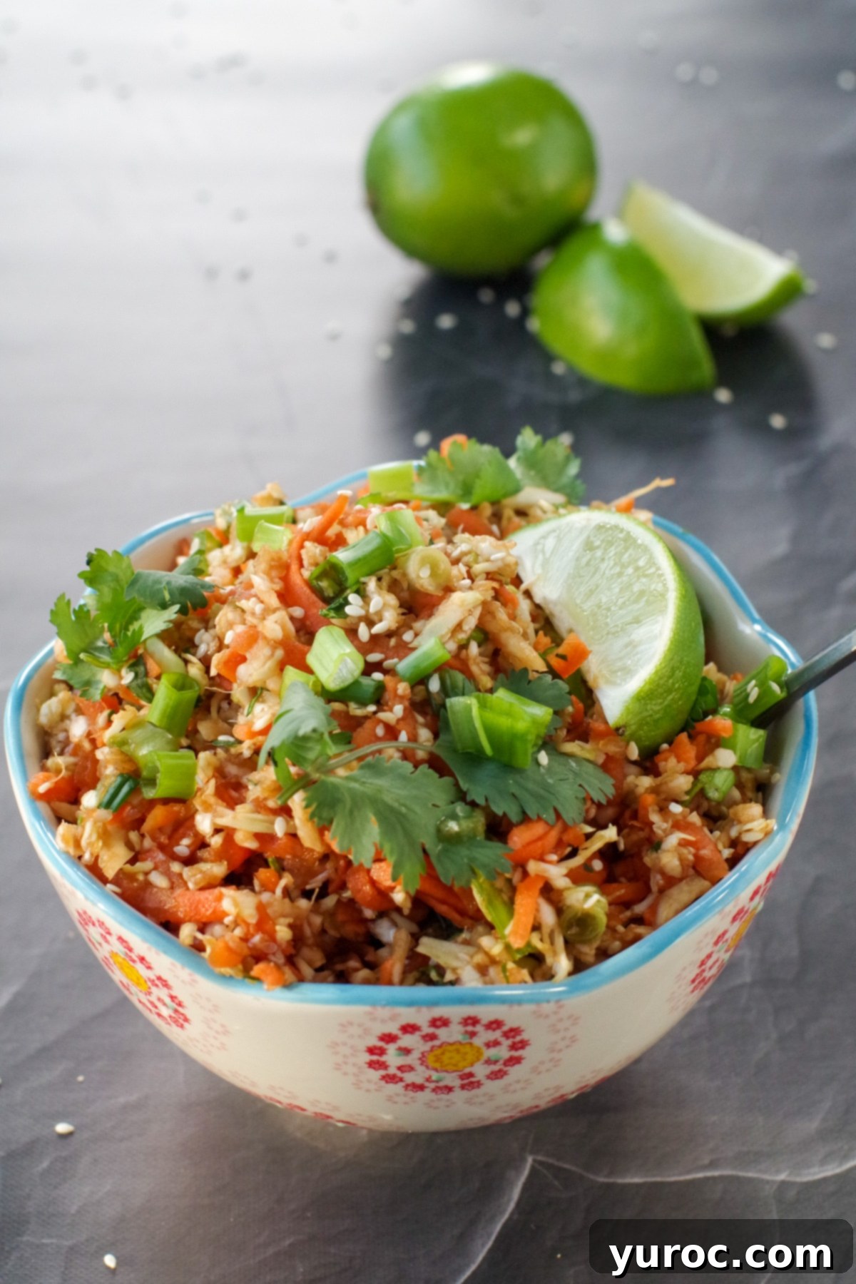 Guilt-Free Coleslaw 5 Bowl of vibrant Asian coleslaw with fresh limes in the background, highlighting its fresh appeal