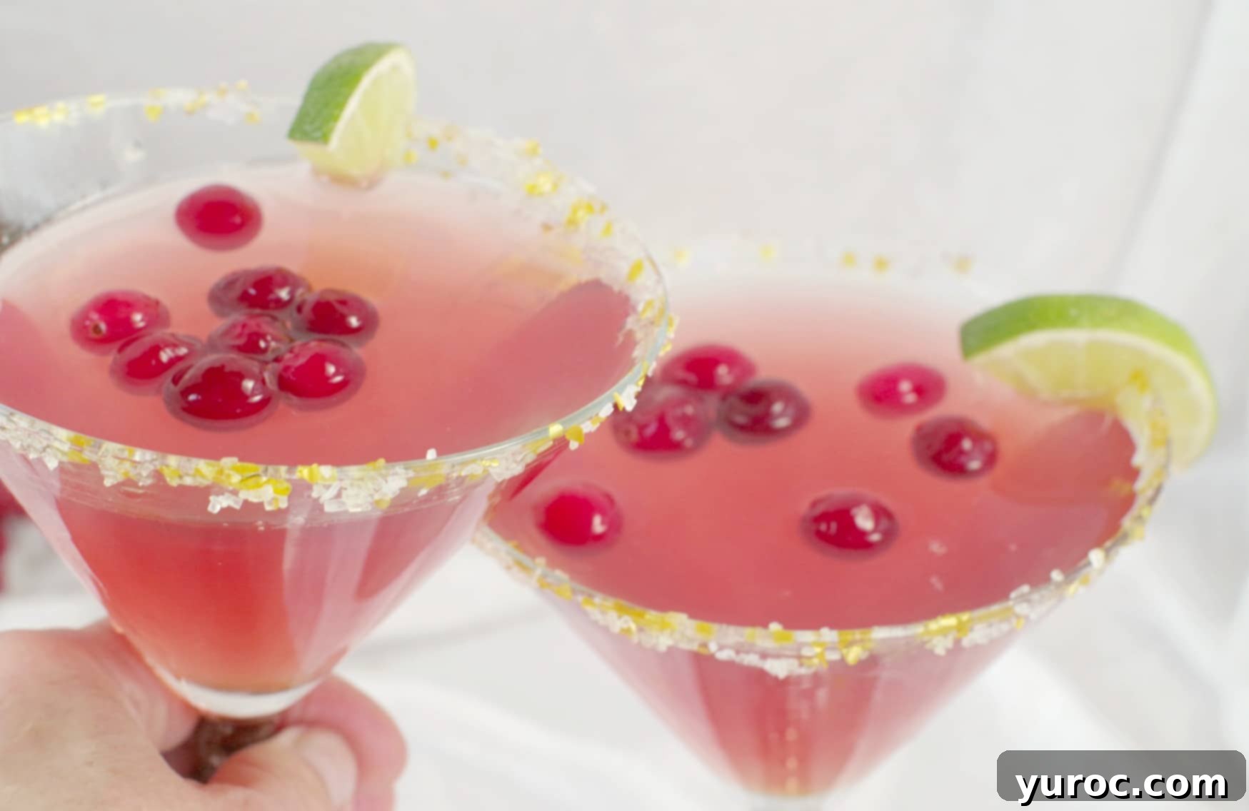 Two Cranberry Cosmo Mocktails with a festive sugar rim and lime garnish.