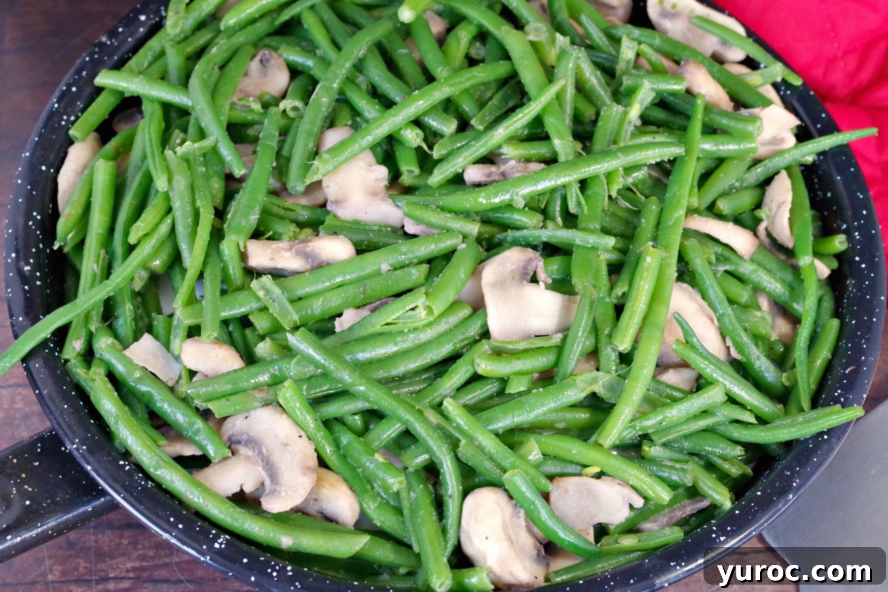 Close up of green beans and mushrooms sautéing in a skillet with garlic and onion powder