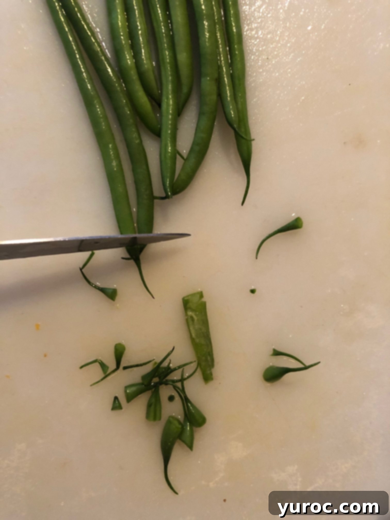 beans with stringy ends being cut off, demonstrating proper trimming technique