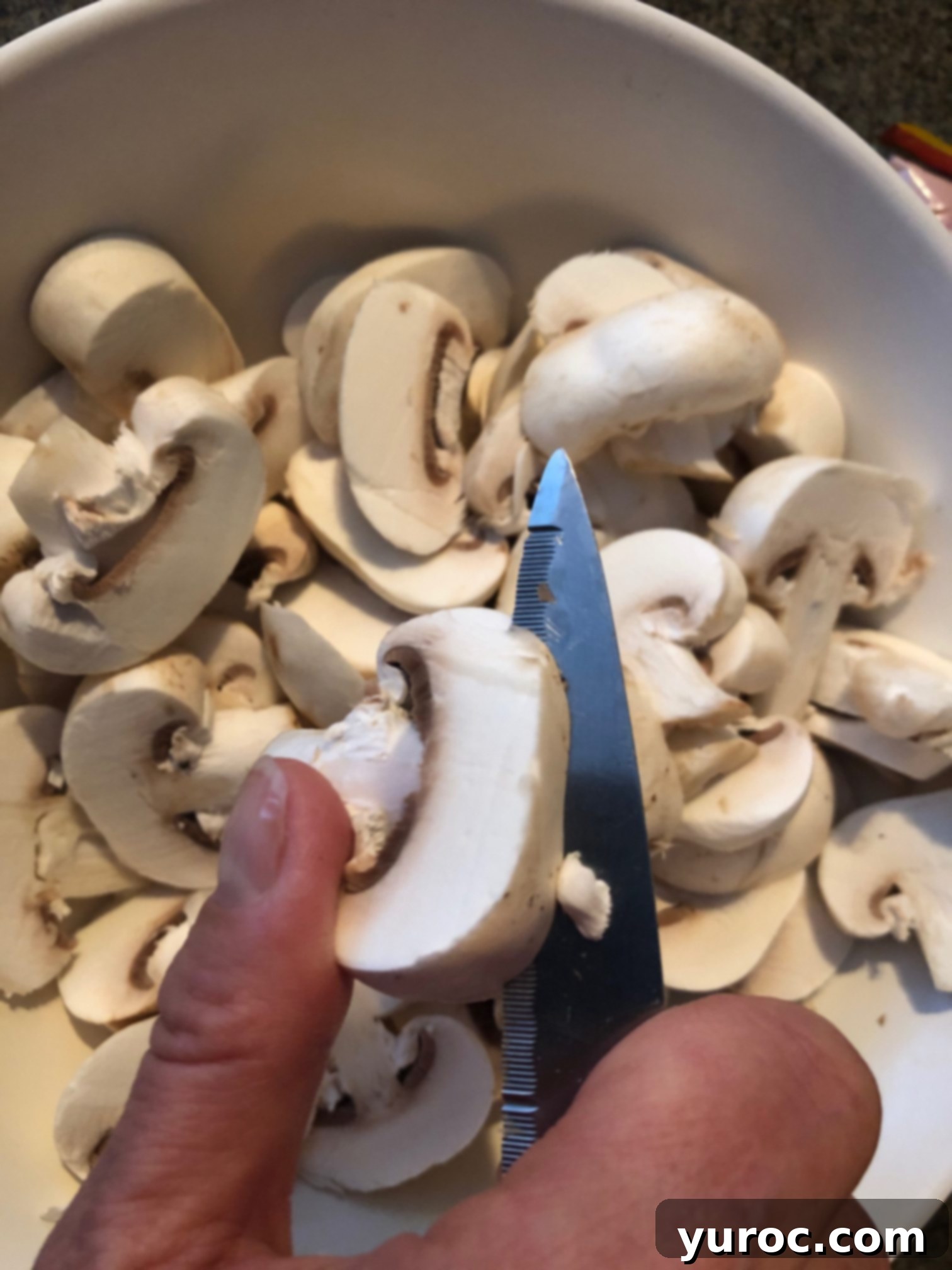 mushrooms being sliced on a cutting board, showing uniform thickness